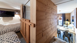 A room with a wooden partition, a television, a dining area with chairs and a table, and a large mirror. - Immodreams - Le Cocooning - Avoriaz (Avoriaz)