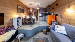 A modern interior with wooden walls, a dining area, kitchen, and a living room with a sofa and ottomans. - Immodreams - Le Cocooning - Avoriaz (Avoriaz)