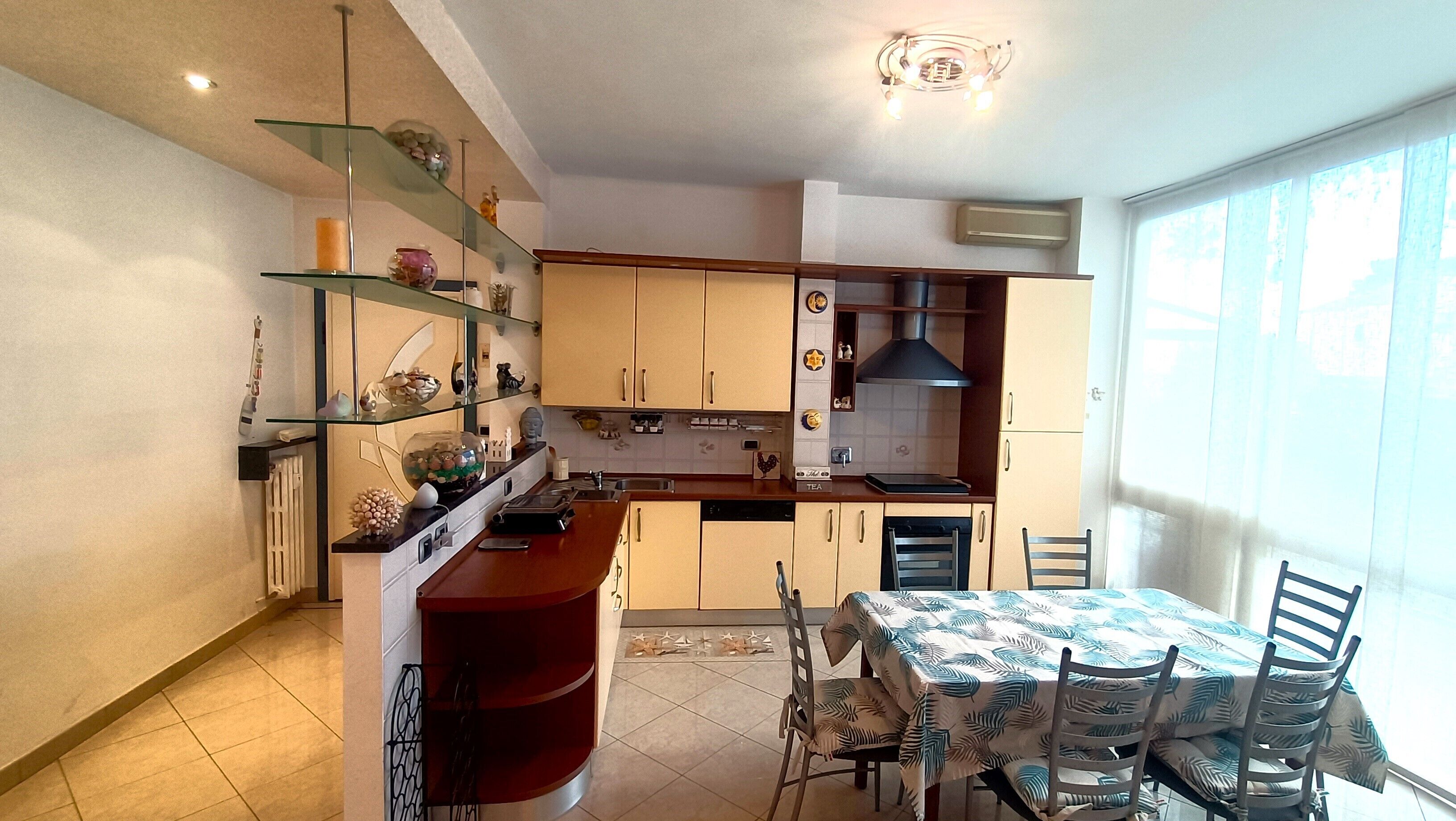 A compact kitchen with a dining area, featuring a built-in oven, a sink, and a window providing natural light.