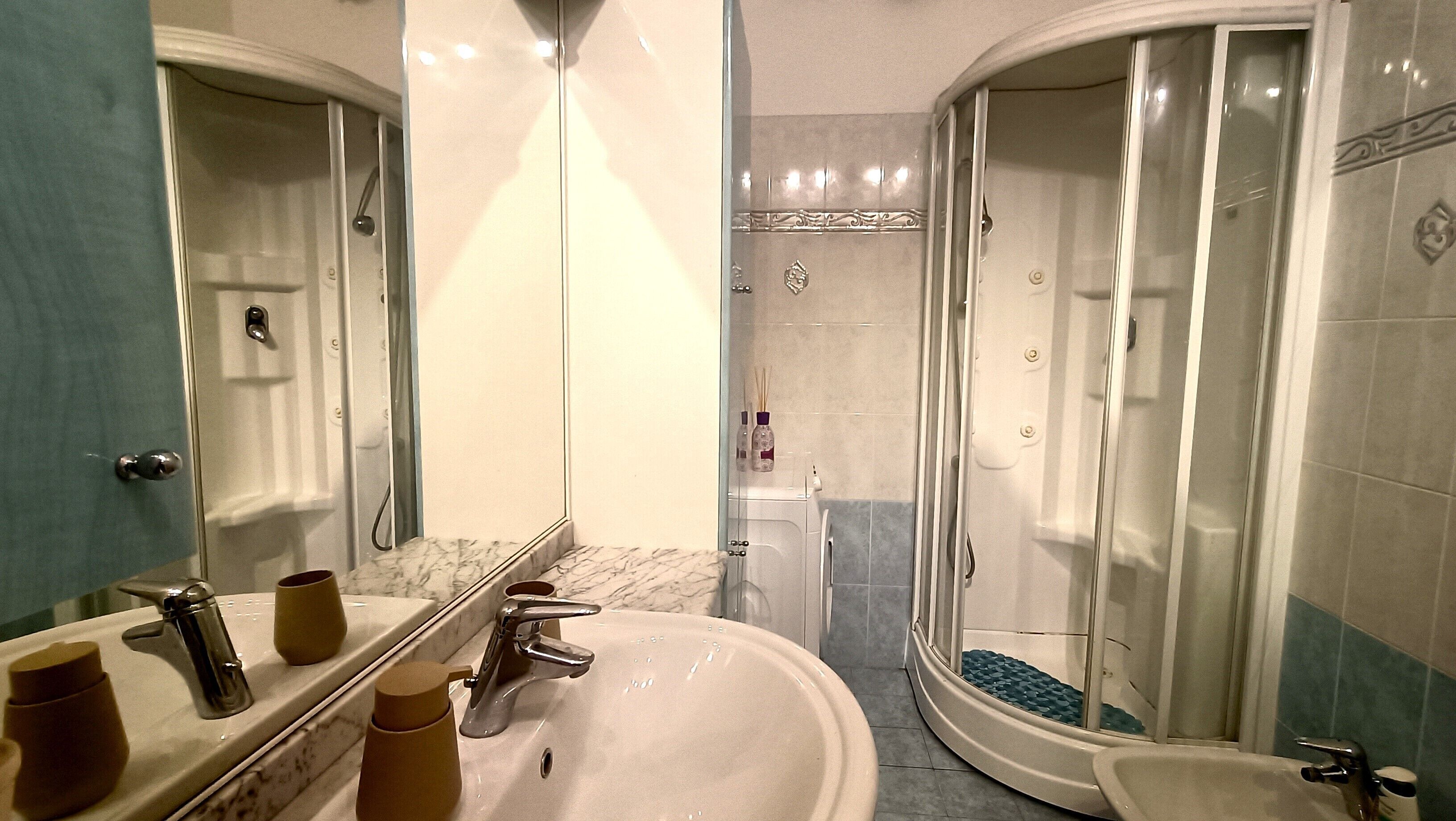 Un baño con un espejo grande, un lavabo, una ducha e inodoro.