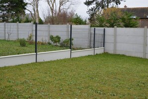 A fenced backyard with a grassy area and a low wall.