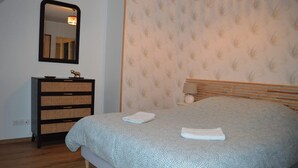 Una camera da letto con un letto, una cassettiera, uno specchio e carta da parati decorata.