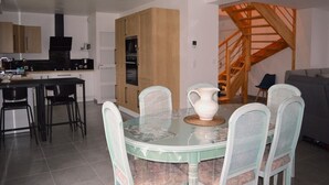 Una cucina moderna con zona pranzo, che include un tavolo rotondo con sedie, un boccale bianco e una scala in legno.