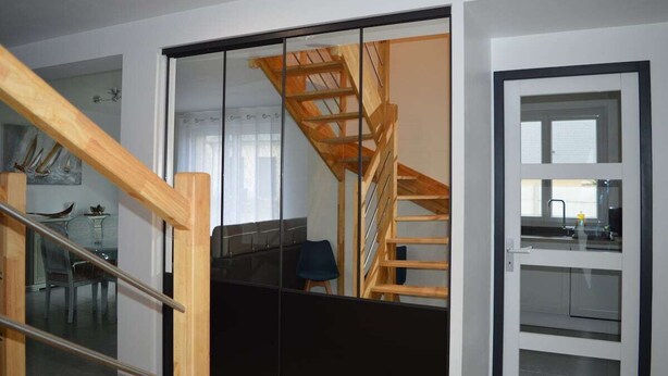 Un interno moderno con una scala in legno, una porta in vetro e un angolo cottura.