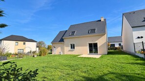 A residential property with a well-maintained lawn, a two-story house with a sloped roof, and a neighboring building. - Les Embruns, Maison Neuve Près des Plages (Asnelles)