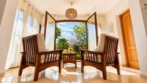 A room with two wooden chairs, a table, and a view of a garden through a window. - Mediterranean Villa in Costa Brava with Pool, Garden, and Close to Beach (Calonge)