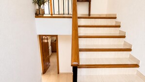 A staircase with wooden steps and a handrail, leading to a landing with a potted plant. - Mediterranean Villa in Costa Brava with Pool, Garden, and Close to Beach (Calonge)