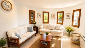 A living room with two sofas, a coffee table, a clock, and framed pictures on the wall. - Mediterranean Villa in Costa Brava with Pool, Garden, and Close to Beach (Calonge)