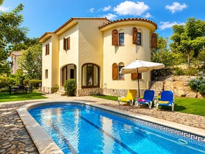 A two-story house with a swimming pool, outdoor seating, and a stone staircase.