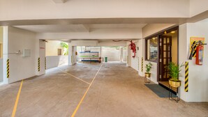 A spacious indoor area with a clear path leading to a reception desk, potted plants, and a fire extinguisher mounted on the wall. - Iyla Apart Hotel (Puducherry)