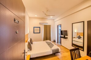 A hotel room with a bed, a TV, a ceiling fan, and an air conditioning unit. - Iyla Apart Hotel (Puducherry)