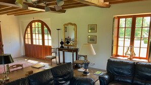 Ein geräumiges Wohnzimmer mit Ledersofas, einem Holztisch und einem großen Bogenfenster.