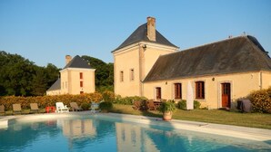 Ein großer Pool mit Liegestühlen und ein Gebäude mit einem geneigten Dach.