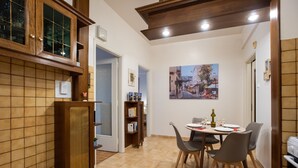 A dining area with a table set for four, a bookshelf, and a painting on the wall. - Blue Ark Gate to History (Athens)