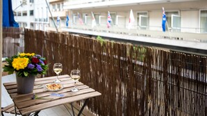 A balcony with a wooden table, a vase of flowers, and two glasses of wine. - Blue Ark Gate to History (Athens)