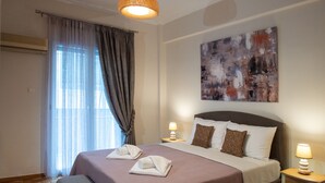 A neatly made bed with towels, a bench, and a bedside table with a lamp. - Blue Ark Gate to History (Athens)