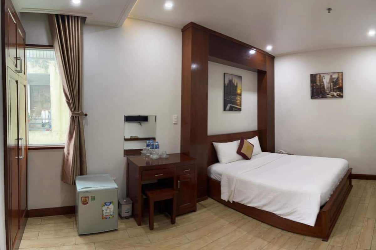 Une chambre d’hôtel équipée d’un lit, d’un bureau, d’une chaise et d’un petit réfrigérateur.
