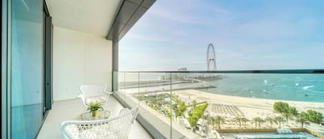 A balcony with a view of a beach, a Ferris wheel, and a swimming pool.