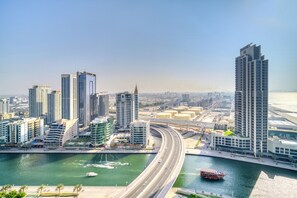 A high-rise building with a modern design, situated near a body of water and a highway. - Address JBR - Mint Stay (Dubai)