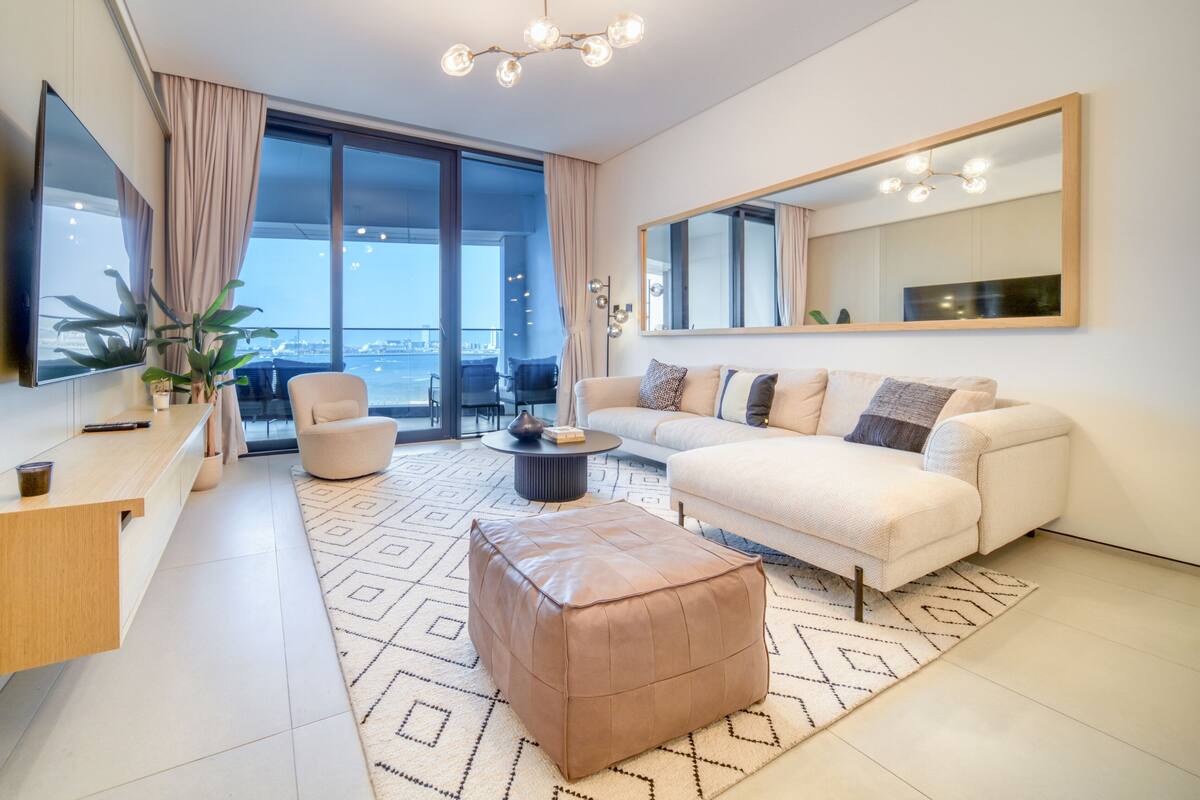 A modern living room with a large window, a sofa, a coffee table, and a TV.