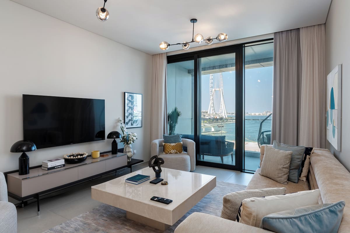 A modern living room with a large flat-screen TV, a coffee table, and a sofa.
