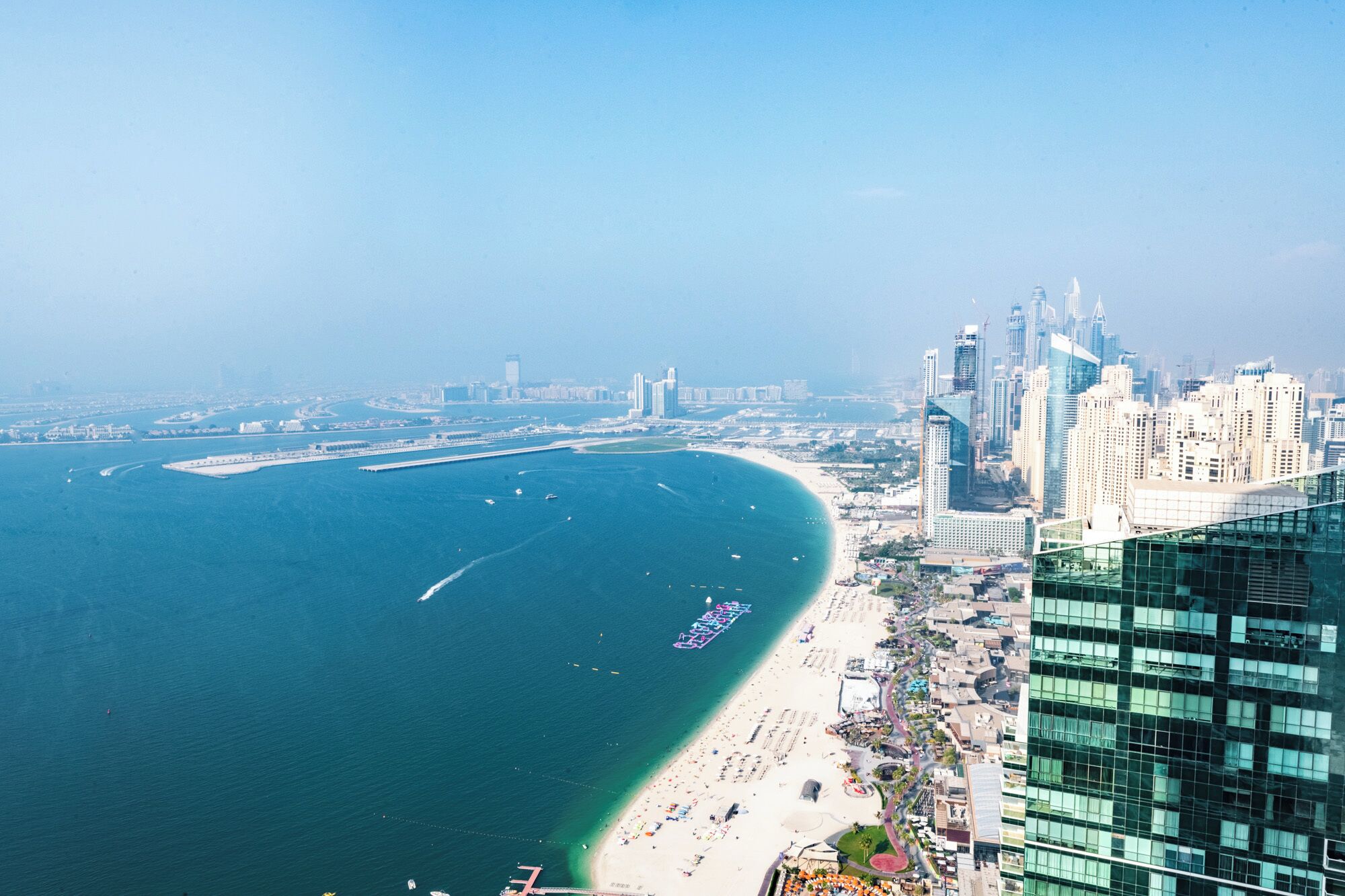 A coastal cityscape with a prominent marina, high-rise buildings, and a beach area.