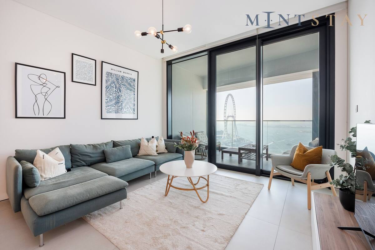 A modern living room with a sectional sofa, a round coffee table, and a large window with a view of a bridge.