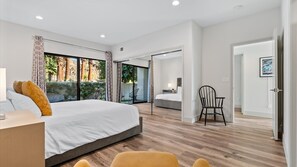 A modern bedroom with a large bed, a chair, and a view of a balcony. - TV205 Trendy 2 bedroom Tennis Villa near LQ Resort (La Quinta)