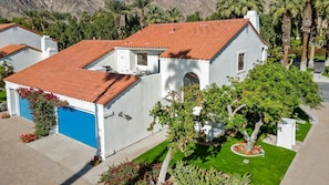 A two-story house with a red-tiled roof, a blue garage door, and a well-maintained lawn. - TV205 Trendy 2 bedroom Tennis Villa near LQ Resort (La Quinta)