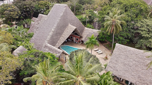 A thatched-roof bungalow with a swimming pool, surrounded by lush greenery and palm trees. - SAFFRON GARDEN MALINDI (Malindi)