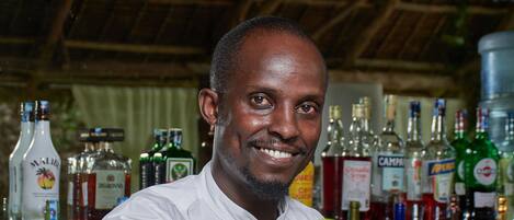 A bartender at a bar with a variety of liquor bottles in the background.