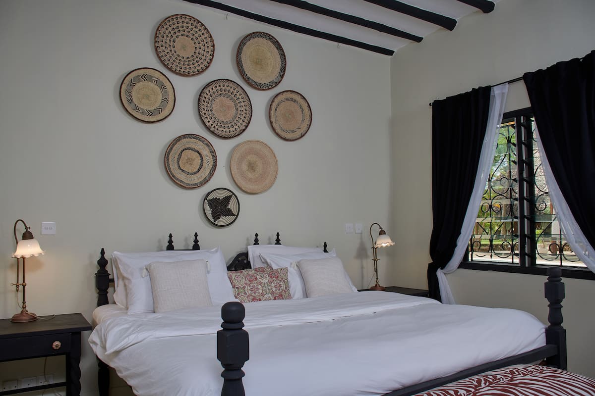 A neatly made bed with white linens, a dark wooden headboard, and a bedside table with a lamp.