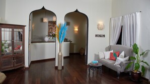 A living room with a sofa, a small table, a cabinet, and a vase with blue feathers. - SAFFRON GARDEN MALINDI (Malindi)