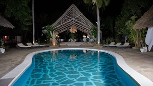 A swimming pool with lounge chairs and a thatched-roof structure in the background. - SAFFRON GARDEN MALINDI (Malindi)