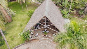 An aerial view of a thatched-roof structure with outdoor seating and a stone-paved area. - SAFFRON GARDEN MALINDI (Malindi)