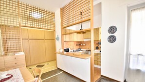 A compact kitchen with wooden cabinets, a small dining area with a table and chairs, and decorative plates on the wall.