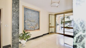A spacious lobby with a large mural, a potted plant, and a glass door leading outside.