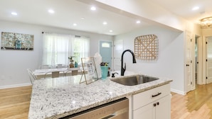 A modern kitchen with a granite countertop, stainless steel sink, and white cabinetry. - Relax in a charming cottage near Nelson 151 featuring inviting living spaces and easy access to Virginia's wineries, breweries, hiking trails, and beautiful Blue Ridge scenery. (Afton)