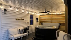 A spa area with a hot tub, a white sofa, and a wooden wall with horizontal slats.
