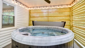 A hot tub in a room with wooden walls and a ceiling fan.