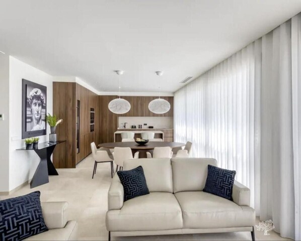 Relax in this stylish living room with a sofa, dining area, and kitchen.