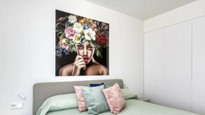 A bedroom with a bed, pillows, a nightstand, and a wall-mounted painting. - Penthouse Limonero 30 (Dehesa de Campoamor)