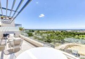 Relax in a spacious living area with a balcony offering breathtaking views of the surrounding landscape and a distant body of water.
