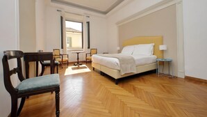 Ein Hotelzimmer mit Bett, Stuhl, kleinem Tisch und Fenster.