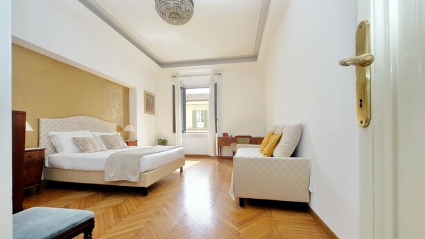 Ein Schlafzimmer mit Bett, Stuhl, Schreibtisch und Blick ins Freie.