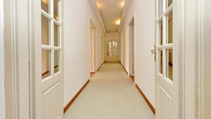 A long, narrow hallway with white walls and doors, leading to a room at the end. - Treasurerome Spanish Steps Family 4BR (Rome)
