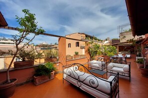 Terraço no telhado com área de estar ao ar livre, plantas em vasos e vista da paisagem urbana.