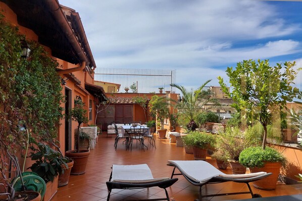Um terraço no terraço com área de jantar, plantas em vasos e vista para a paisagem urbana.