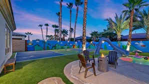 A backyard with a tennis court, outdoor seating, and a slide. - All Inclusive  Super Mario Hideout Arcade PIckleball Pool Slide (Indio)