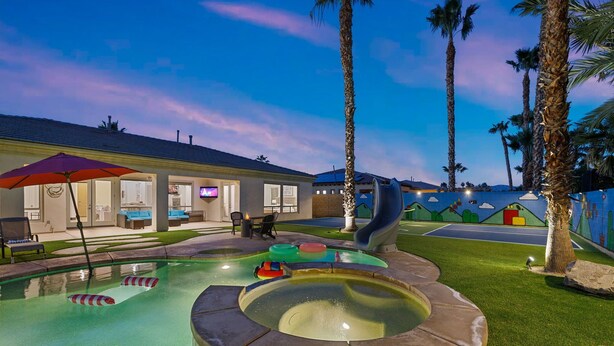 An outdoor pool area with a hot tub, lounge chairs, and a slide. - All Inclusive  Super Mario Hideout Arcade PIckleball Pool Slide (Indio)